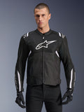 Alpinestars T-SPS Air V2 jacka, textil motorcykeljacka, svart med vita detaljer, stor vit bröstlogotyp, perforerad mesh-design för ventilation, bärs med svarta byxor och handskar