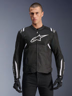 Alpinestars T-SPS Air V2 jacka, textil motorcykeljacka, svart med vita detaljer, stor vit bröstlogotyp, perforerad mesh-design för ventilation, bärs med svarta byxor och handskar