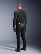 Alpinestars T-Sps Air V2-jacka, textil motorcykeljacka, svart, baksida som visar stor ventilationspanel i mesh och vit Alpinestars-logotyp på nedre delen av ryggen, kombinerad med svarta mc-byxor och handskar för en sportig urban stil.