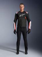 Manlig modell som bär Alpinestars T-Sps Air V2-jacka i Black White Red Fluo, med stora tech-mesh-paneler och framträdande vit logotyp på bröstet och ärmarna, matchad med svarta tekniska körbyxor och handskar, urban sport-motorcykelutrustning