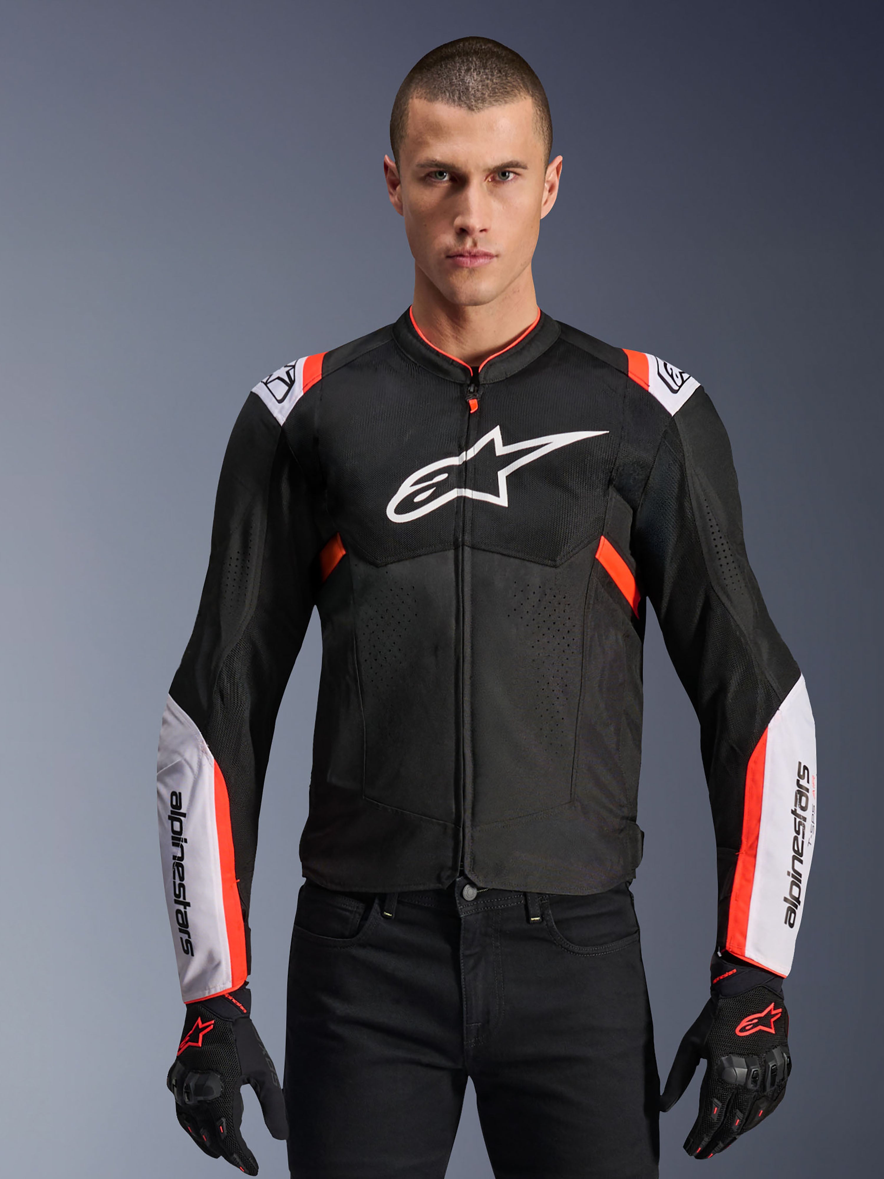 Alpinestars T-Sps Air V2 Jacket, Black with White and Red Fluo accents, motorcycle sport jacket, man wearing a mesh-vented design with large chest logo and branded sleeves, paired with black gloves and pants