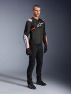 Alpinestars T-Sps Air V2-jacka, Black White Red Fluo, bärs av en manlig modell med svarta mc-byxor och handskar, mc-jacka i textil med stora meshpaneler, vita partier på axlar och underarmar samt en tydlig Alpinestars-logotyp på bröstet.