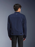 Alpinestars Bruiser Jacket, Dark Blue textile motorcycle jacket, back view on model, workwear-inspired design with a small white Astars logo on the neck, adjustable waist tabs, urban contemporary riding apparel.