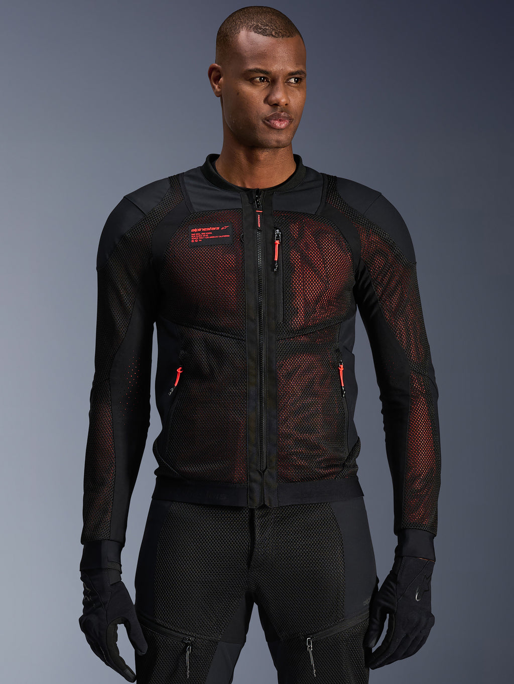 Alpinestars Troop-Air Pro Jacket, teknisk bepansrad motorcykeljacka, svart och röd fluo, med röda dragkedjekläppar och Alpinestars-logotyp, ventilerande meshpaneler med rött underlager, bärs med matchande svarta mc-byxor och handskar