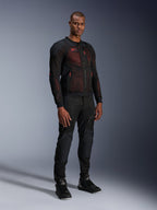 Alpinestars Troop-Air Pro-jacka i Black Red Fluo, teknisk motorcykeljacka i mesh med integrerade skydd, bärs av en manlig modell med matchande svarta skyddsförstärkta byxor och höga boots, studiofotografi i helfigur.