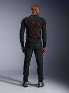 Alpinestars Troop-Air Pro-jacka i Black Red Fluo, vy bakifrån på modell, teknisk meshjacka med skydd och ventilerande paneler, röd logotyp på övre delen av ryggen, bärs med svarta byxor och sneakers, urban motorcykelutrustning