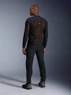 Alpinestars Troop-Air Pro-jacka i Black Red Fluo, ryggvy på en modell, med en stor ryggpanel i 2D-tech mesh med synlig röd insida, kombinerad med svarta tekniska körbyxor och svartgrå stövlar, modern urban design för en bepansrad motorcykeljacka.