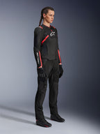 Kvinnlig förare i Alpinestars Stella T-SPS Air V2-jacka, svart och Diva Pink, motorcykeljacka i textil för damer med meshpaneler och rosa detaljer, matchad med svarta mc-byxor och handskar, helkroppsvy i studiomiljö