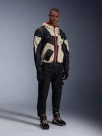 Man som står i komplett urban motorcykelutrustning, med Alpinestars Speedstreet Shoes i Black Almond Hot Orange och en Mogress Air Jacket i svart och krämfärgat, matchande svarta byxor och handskar, streetwear-inspirerad skyddsutrustning för stadskörning