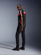 A man wearing the Alpinestars T-Dyno Air Jacket in Black, Bright Red, and Ecru, vintage-inspired textile motorcycle jacket with mesh panels, bold branding on the sleeve, paired with black pants and boots for a modern biker look