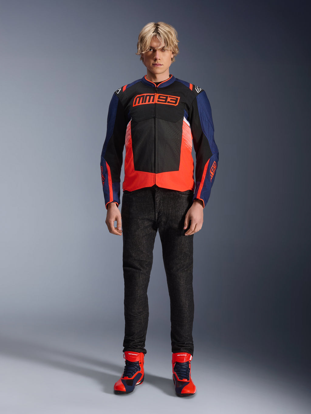 Alpinestars MM93 T-SPS Air V2-jacka, marinblå och svart med röda fluo-detaljer, med den karakteristiska MM93-logotypen på bröstet, bärs med svarta MC-byxor och matchande blå och röda stövlar, urban MC-outfit