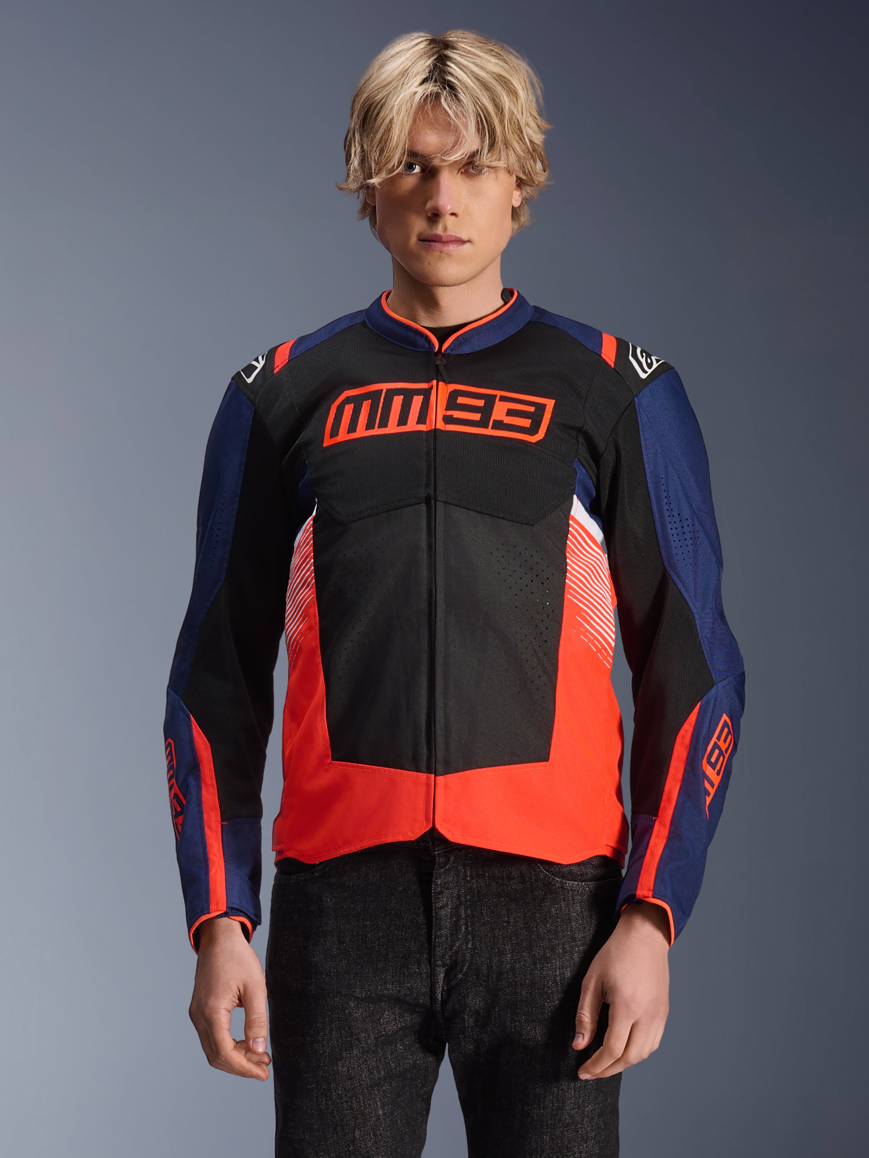 Alpinestars MM93 T-SPS Air V2 jacka, motorcykeljacka i textil, marinblå, svart och fluorescerande röd, buren av en person, med framträdande MM93-logotyp på bröstet, meshpaneler för ventilation och modern färgblockerad design