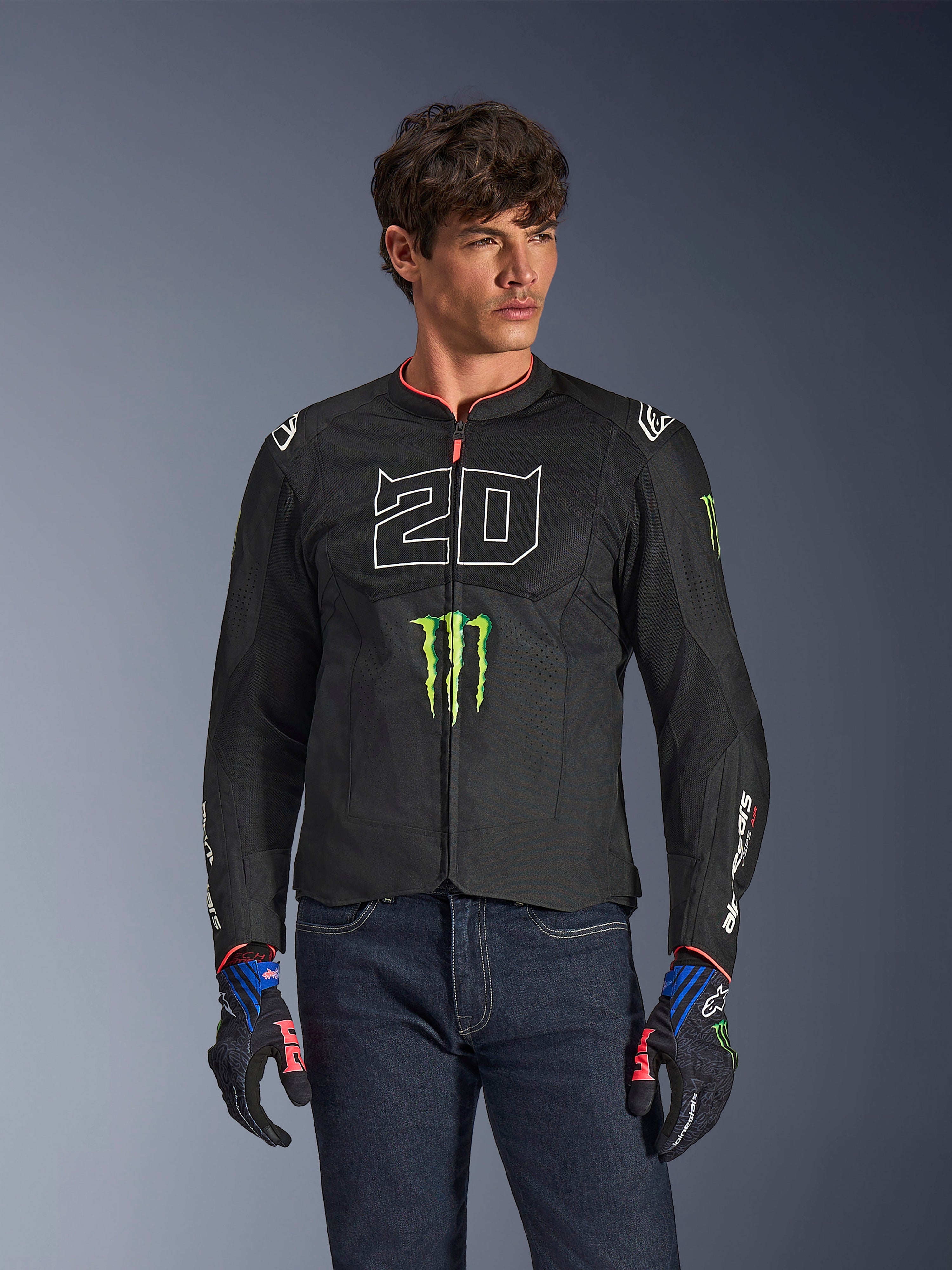 Alpinestars FQ20 T-SPS Air V2 Monster-jacka, svart motorcykeljacka med stor vit '20' och grön Monster Energy-logotyp, bärs av en manlig modell med mörka jeans och matchande handskar, lättviktig mesh-konstruktion för stadskörning