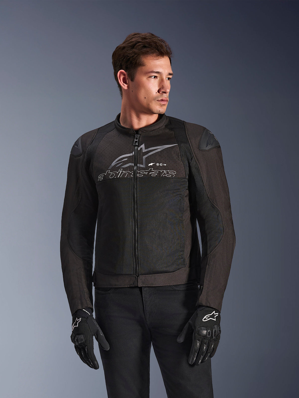 Alpinestars SMX Air-jacka i Black Anthracite, textilmotorcykeljacka med högflödes meshpaneler, stor grå Alpinestars-logotyp och text på bröstet, DFS Lite-axelsliders, bärs av en modell med svarta körhandskar, sportig körstil.