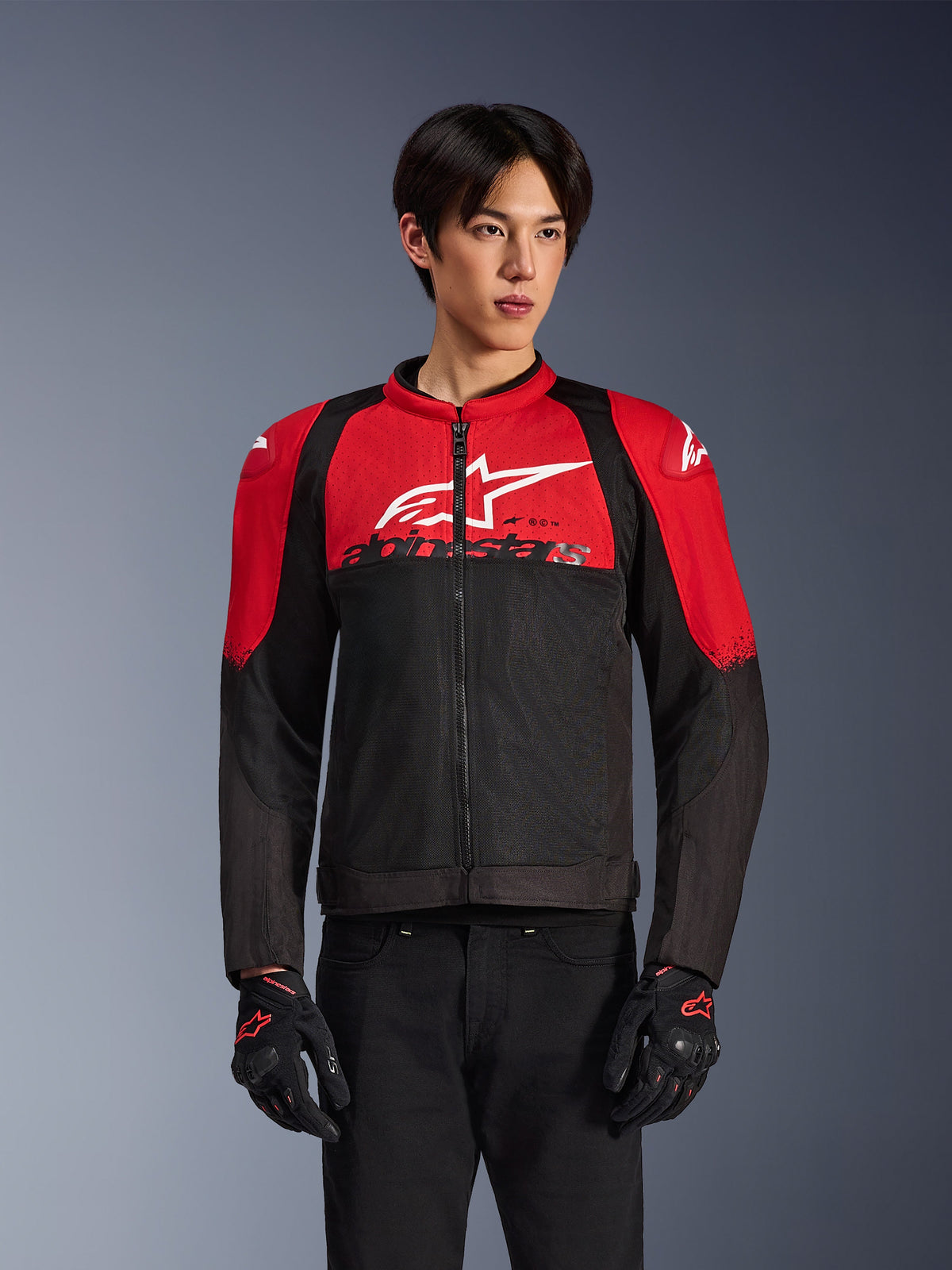 Alpinestars SMX Air Jacket, Motorcycle Mesh Jacket, Bright Red and Black, worn by a model with black riding gloves, featuring a large white logo on the chest, ventilated textile construction with red shoulder panels and black sleeves, sporty performance gear for warm-weather riding