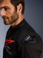 Alpinestars SMX Air-jacka, svart och röd, närbild på DFS Lite-axelskydd med stjärnlogotyp, bärs av en man med skägg, racing- och sportmotorcykeljacka i textil.