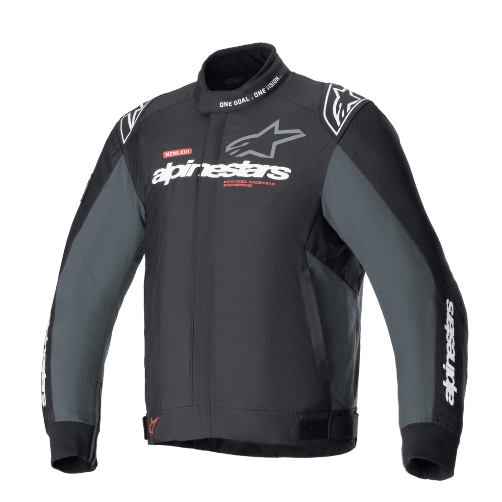 Alpinestars Monza Sport Jacket, Black Tar Gray motorcykeljacka i textil, hög krage med texten 'ONE GOAL. ONE VISION.', vita och grå Alpinestars-logotyper på bröstet, stjärnlogotyper på axlarna, röda grafiska detaljer, justerbara flikar i midjan, stilren teknisk design.
