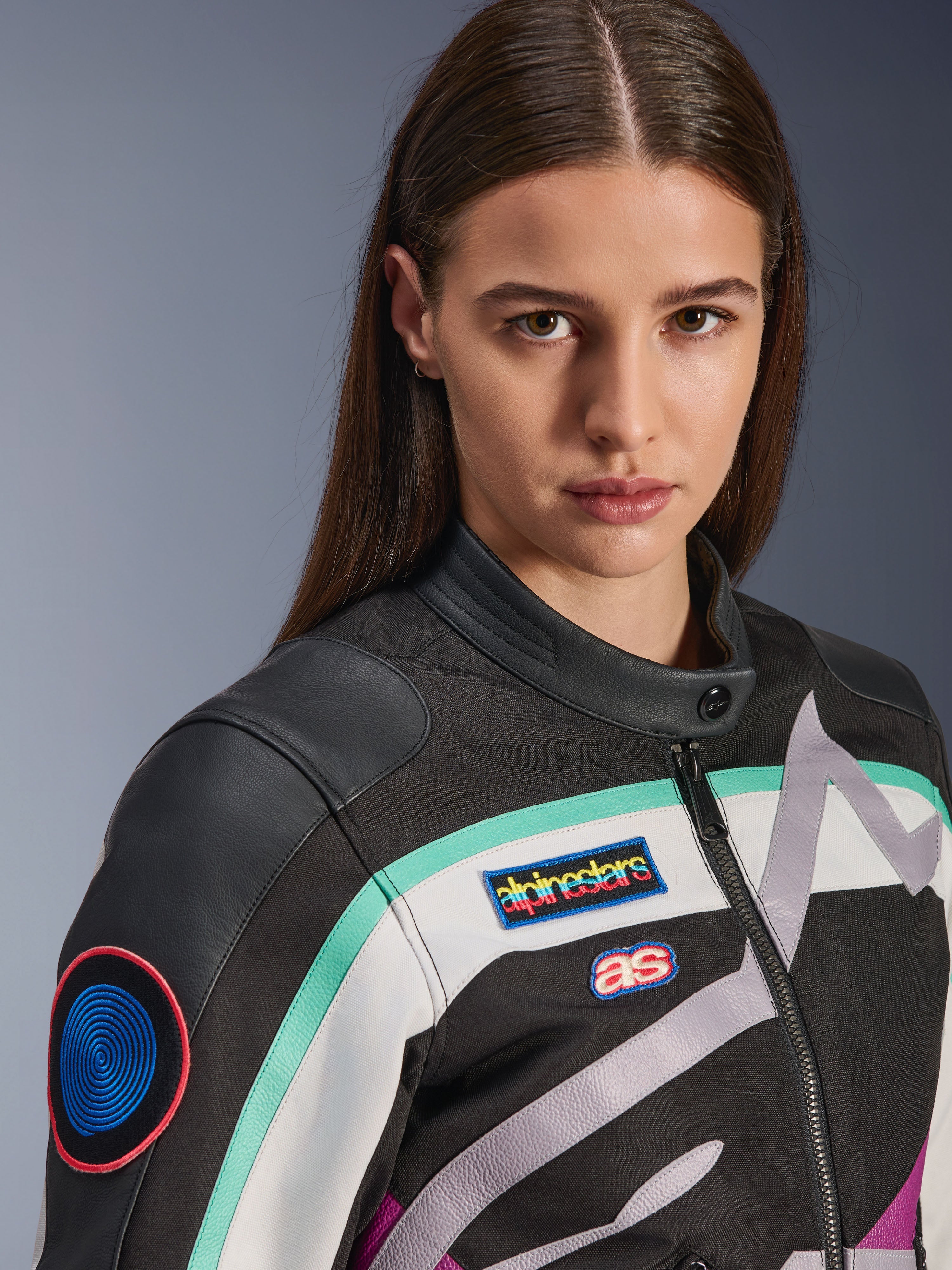 Alpinestars Idles damjacka, motorcykeljacka, svart, benvit och lila med turkosa accenter, närbild med färgglada Alpinestars heritage-märken och axeldetaljer i getskinn, vintageinspirerad design för stadskörning.