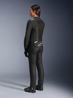 Alpinestars Stella T-Sps Air V2-jacka, svart och vit, vy bakifrån som visar meshpaneler och logotyp på nedre ryggen, matchad med svarta mc-byxor och motorcykelskor, sportig textilutrustning för kvinnor