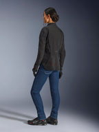 Kvinna som bär Alpinestars Stella Aeroshell Airflow-jacka i Black Anthracite, trekvartsvy bakifrån som visar meshpaneler som andas och förlängd bakre profil, kombinerad med blå MC-jeans i denim och svarta Alpinestars-skor