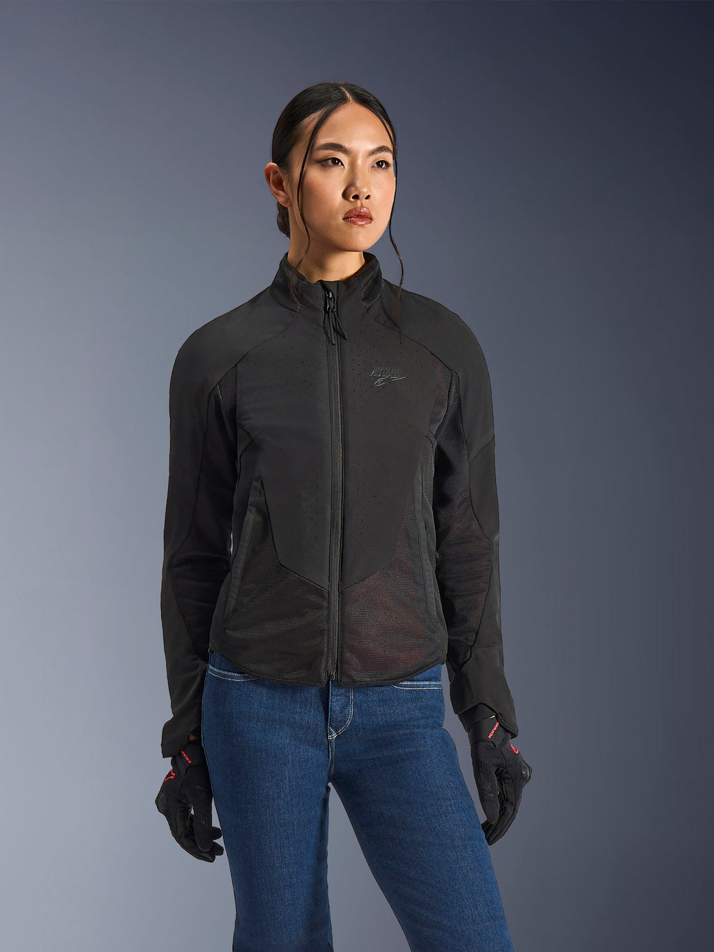 Alpinestars Stella Aeroshell Airflow-jacka, motorcykeljacka för dam, svart antracit, bärs av modell med blå jeans och svarta handskar, med laserperforerad softshell och nätpaneler för högt luftflöde, ergonomisk sportdesign.