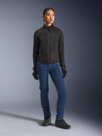 Kvinnlig förare som bär Alpinestars Stella Aeroshell Airflow-jacka i svart, med laserperforerad ventilation och nätpaneler, stylad med blå MC-jeans och svart motorcykelutrustning, modern sportig och urban estetik