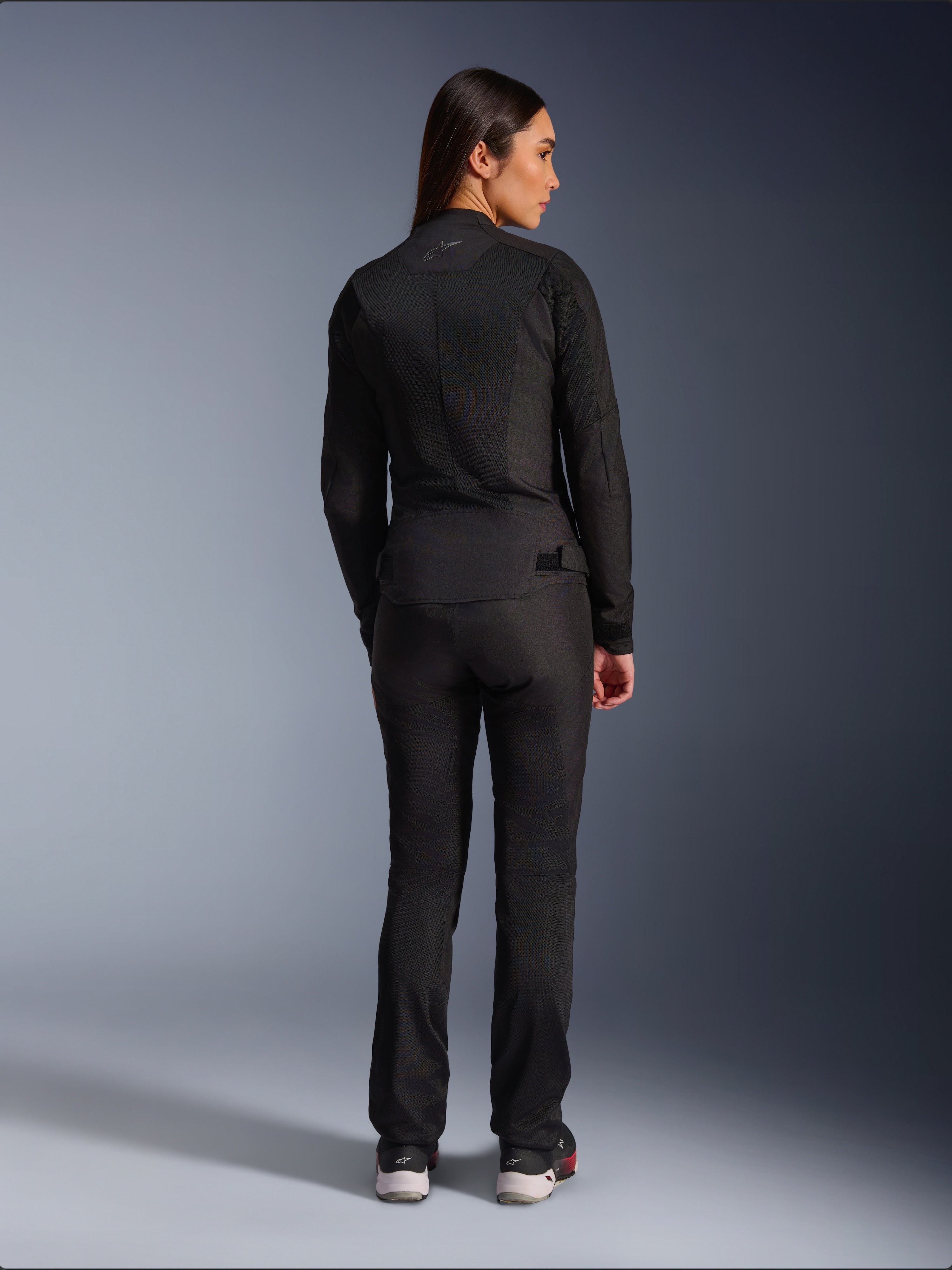 Alpinestars Stella C-1 Air Jacket, Women’s Textile Motorcycle Jacket, Black, rear view showing mesh construction and subtle logo on the upper back, worn with matching black riding pants, urban contemporary style