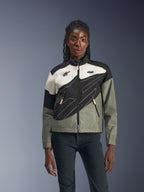 Kvinna som bär Alpinestars Stella Moshell-jackan, urban motorcykeljacka i Black Fur Gray Off White och rosa, asymmetrisk design med teknisk grafik, rosa dragkedjekläppar och Alpinestars-logotyper, samtida streetwear-stil för stadskörare