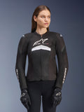 Alpinestars Stella T-GP Plus R V4 Airflow Jacket, Women's Motorcycle Racing Jacket, Black with White and Gray Accents, Textured Mesh Design, Logo on Chest and Sleeves, Worn with Matching Black and White Gloves