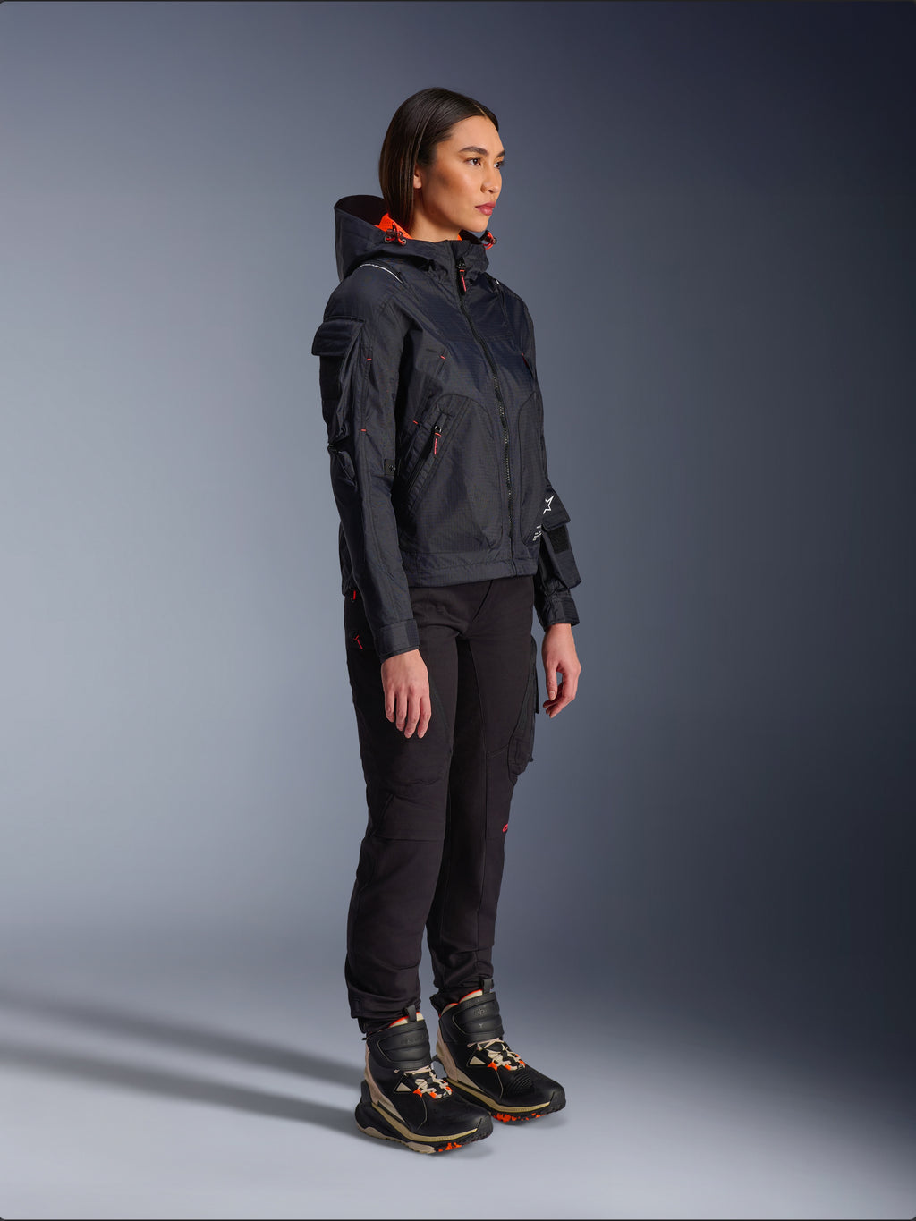 Alpinestars Actea Women's Pants in Black, regular fit with cargo pockets, styled with a black Molly Air Jacket with orange accents and high-top riding shoes, contemporary urban motorcycle apparel for women