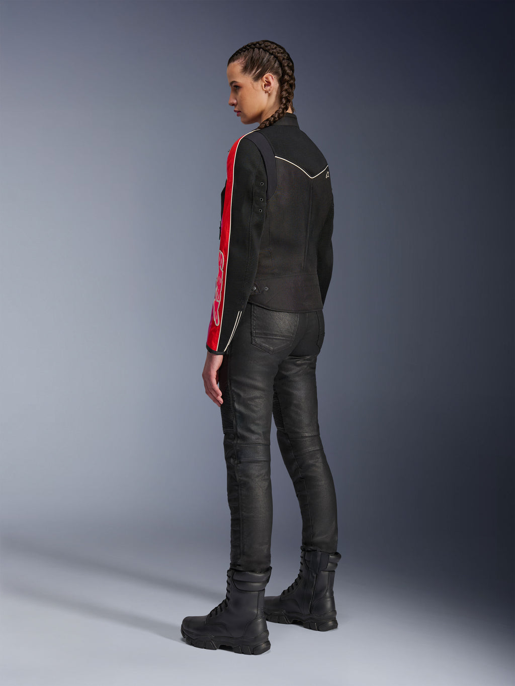 Woman wearing Alpinestars Stella T-Dyno Air Jacket in Black Bright Red Fuchsia, paired with black riding pants and black boots, side-profile view highlighting the red and fuchsia sleeve graphics and tailored biker fit.