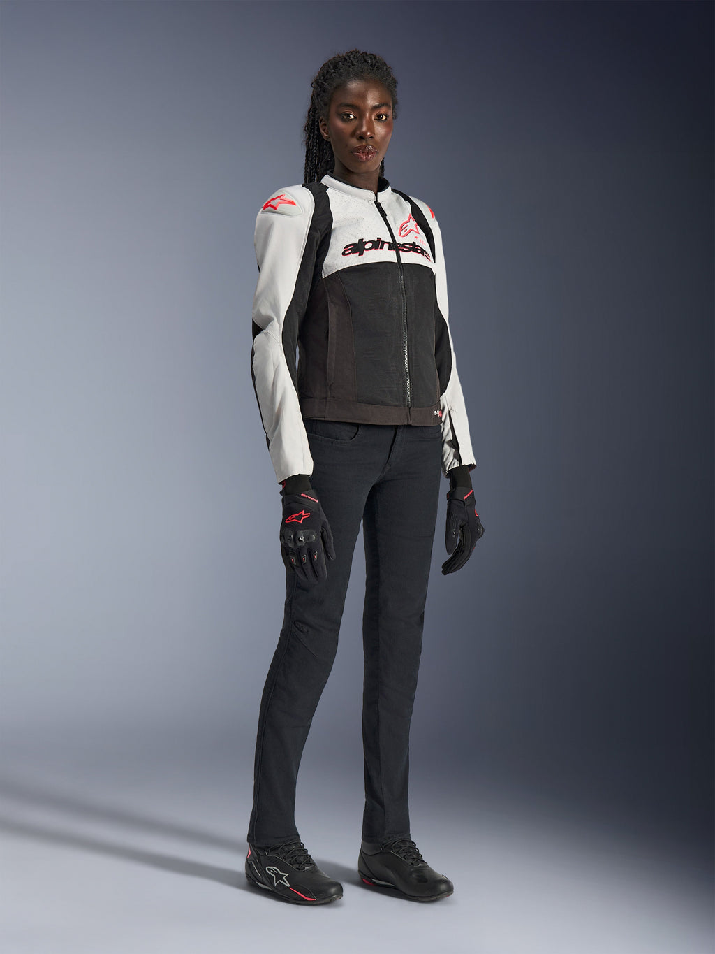Alpinestars Stella SMX Air-jacka för dam i Ice Gray Black Coral Fluo, bärs av en kvinnlig modell med svarta mc-byxor och handskar, med mesh-konstruktion och korallröda logotyper, sportig motorcykelutrustning för kvinnor