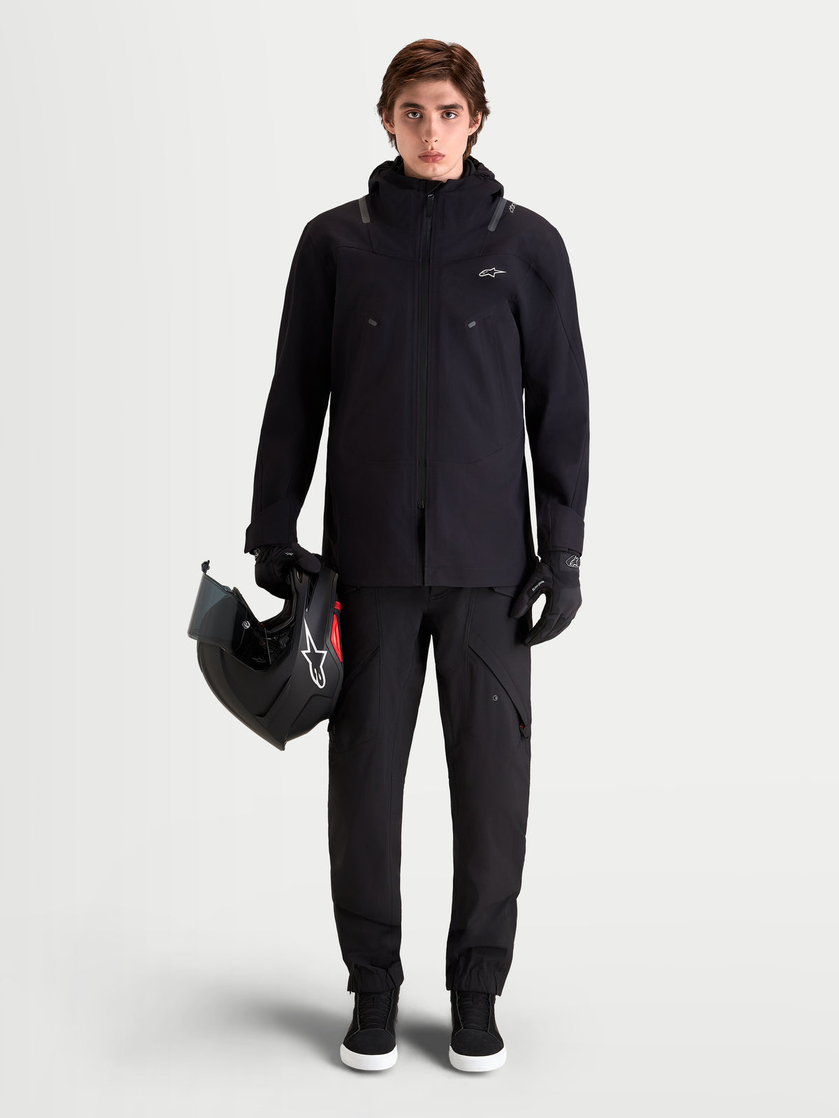 Alpinestars Juggernaut V2 Drystar byxor, svarta urbana motorcykelbyxor för herr, helhetsbild framifrån på modell iklädd matchande jacka och hjälm med vattentät textilkonstruktion