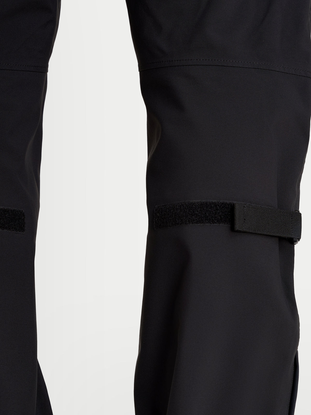 Alpinestars Juggernaut V2 Drystar byxor, svarta vattentäta motorcykelbyxor för herr, närbild som visar justeringar vid benet och teknisk textilkonstruktion