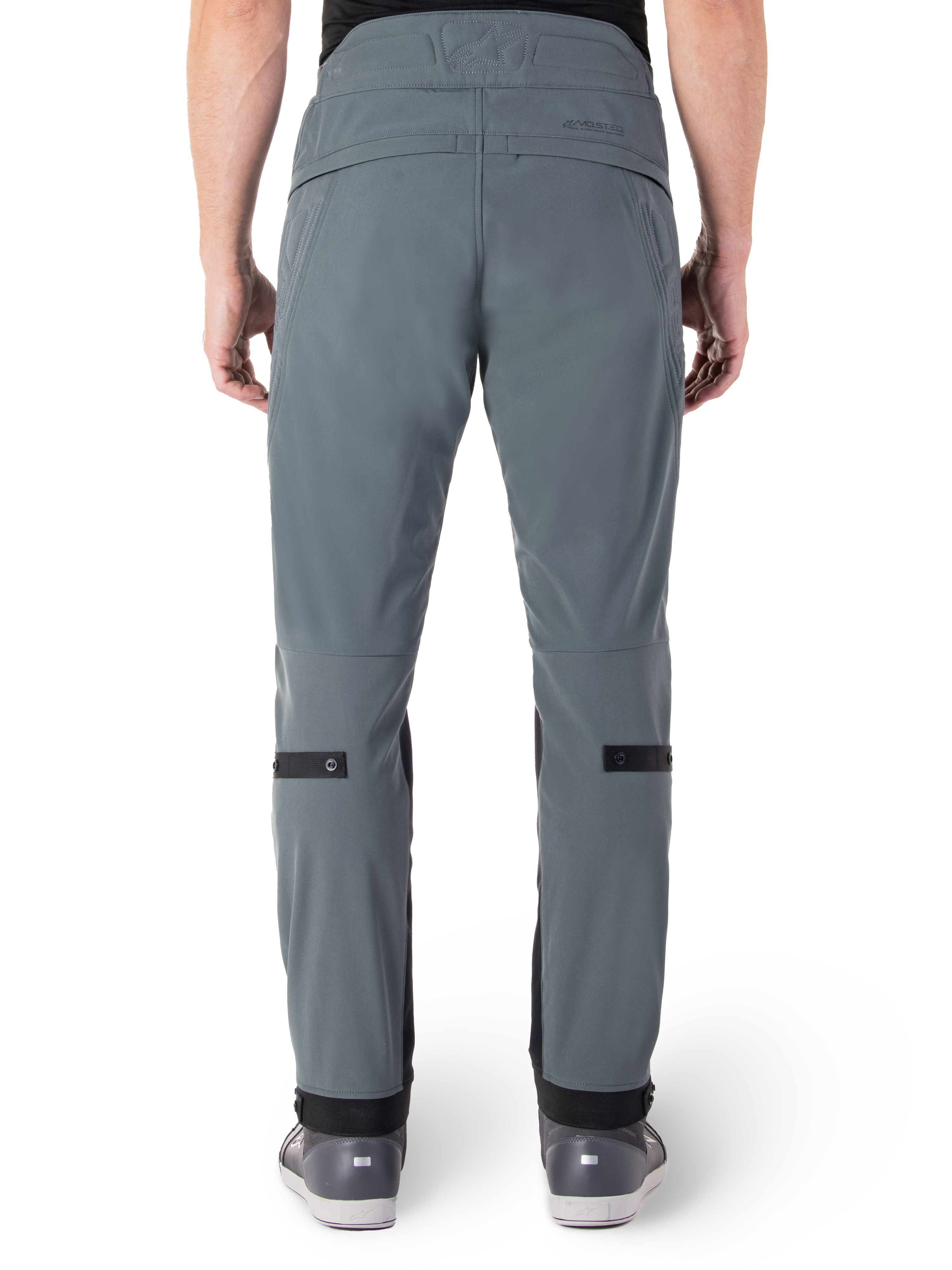 Alpinestars Alden-byxor, Urban Gray, baksida av urbana motorcykelbyxor för män, smal passform nedanför knät med svarta justeringsremmar vid vaderna, högmidjad design med MO.ST.EQ.-logotyp på bakre oket, bärs med grå mc-skor