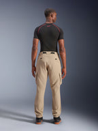Alpinestars Flex-AST Cargo-byxor, ljusbeige, sedda bakifrån på en modell, regular tapered-passform med cargofickor på sidorna och elastiska benslut, matchade med en svart kortärmad baströja med röda detaljer, urban motorcykelutrustning