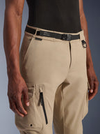 Alpinestars Flex-AST Cargo Pants - Short, ljusbeige, närbild av midja och lår, med ett svart justerbart bälte med Alpinestars-märkning, D-ring i metall och funktionella cargofickor med dragkedjor och lock med tryckknappar, urban modern motorcykelutrustning