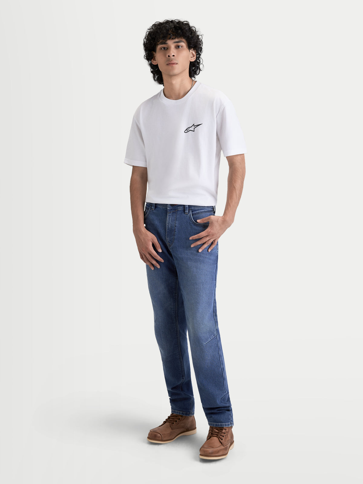 Alpinestars Flex-AST 7 Denim byxor, ljusblå motorcykeljeans för herr med skyddande denim och COOLMAX-komfort, framifrån på manlig modell i vit t-shirt och bruna kängor