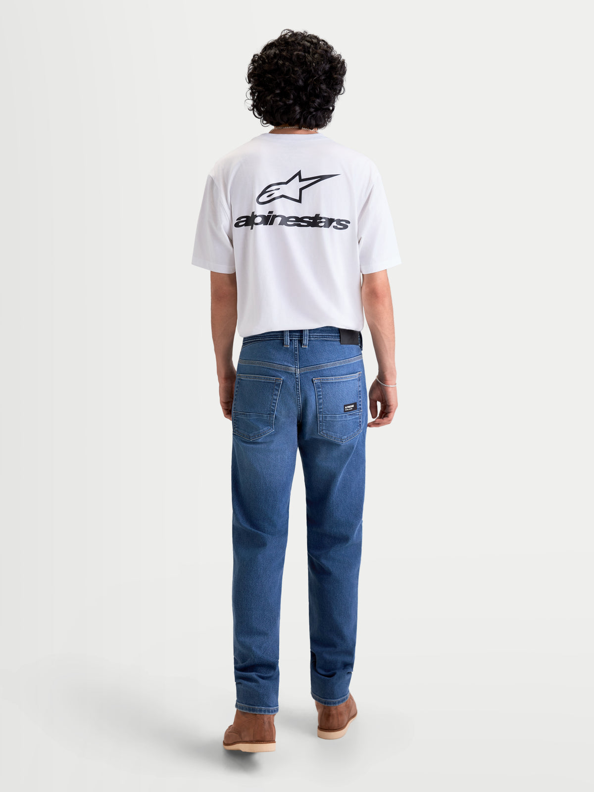 Alpinestars Flex Ast 7 Denim byxor, ljusblå motorcykeljeans för herr med AA-klassad enkellagerskonstruktion, vy bakifrån på en modell iklädd en vit t-shirt