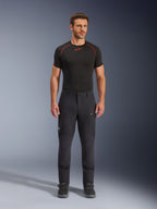 Alpinestars Flex-AST Explorer Pants, svarta äventyrs- och touringbyxor för motorcykel, man som bär åtsittande textilbyxor med cargofickor med dragkedja och förstärkta paneler, matchade med ett svart underställ och motorcykelstövlar, slitstarkt skydd för äventyrskörning