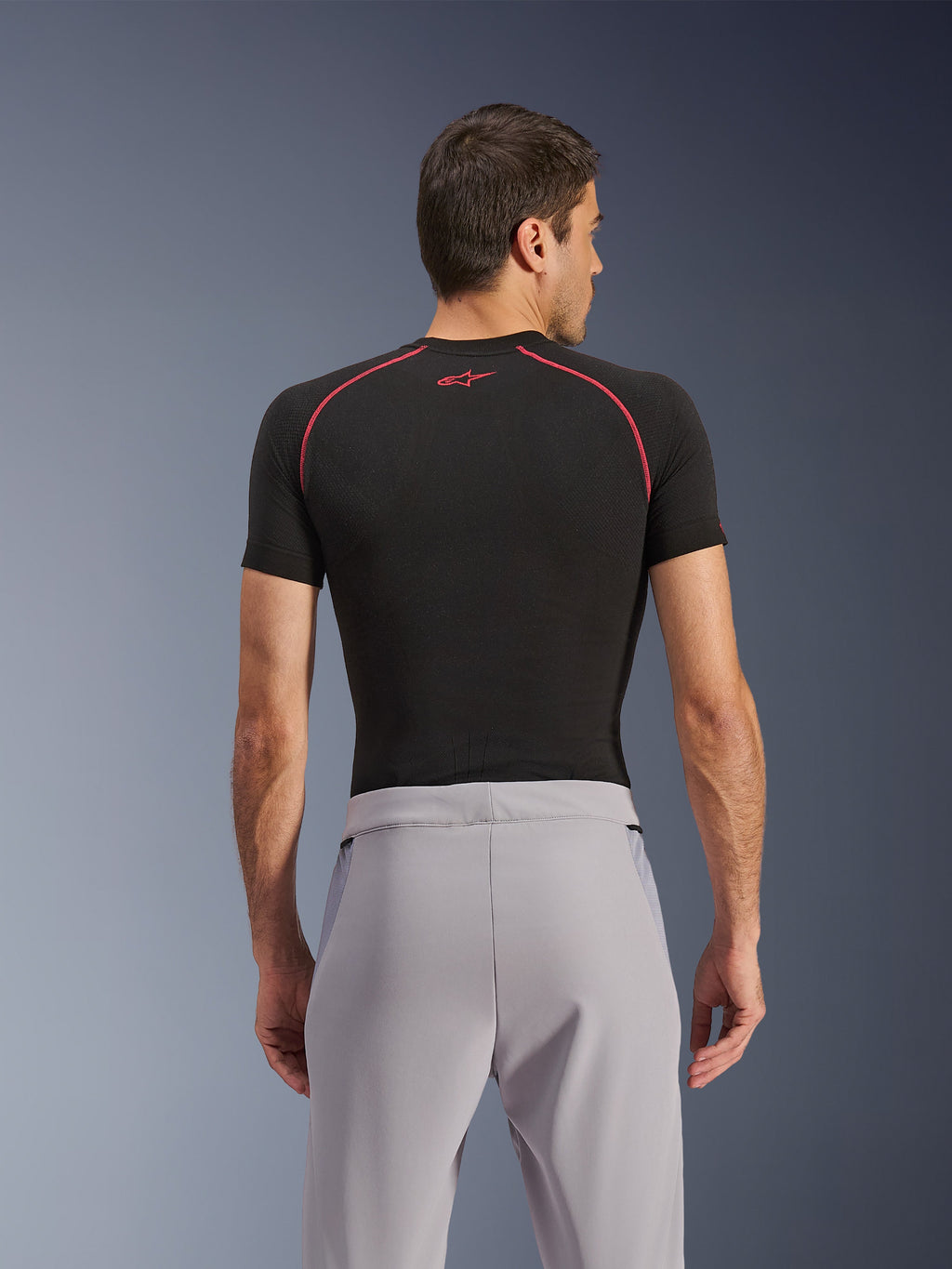 Alpinestars Aeroshell Airflow byxor, Mid Gray, vy bakifrån, bärs med ett svart kortärmat underställ med röda sömmar och logotyp, med lätt stretch-softshell och meshpaneler för maximal ventilation, ergonomisk sportpassform för motorcykelkörning