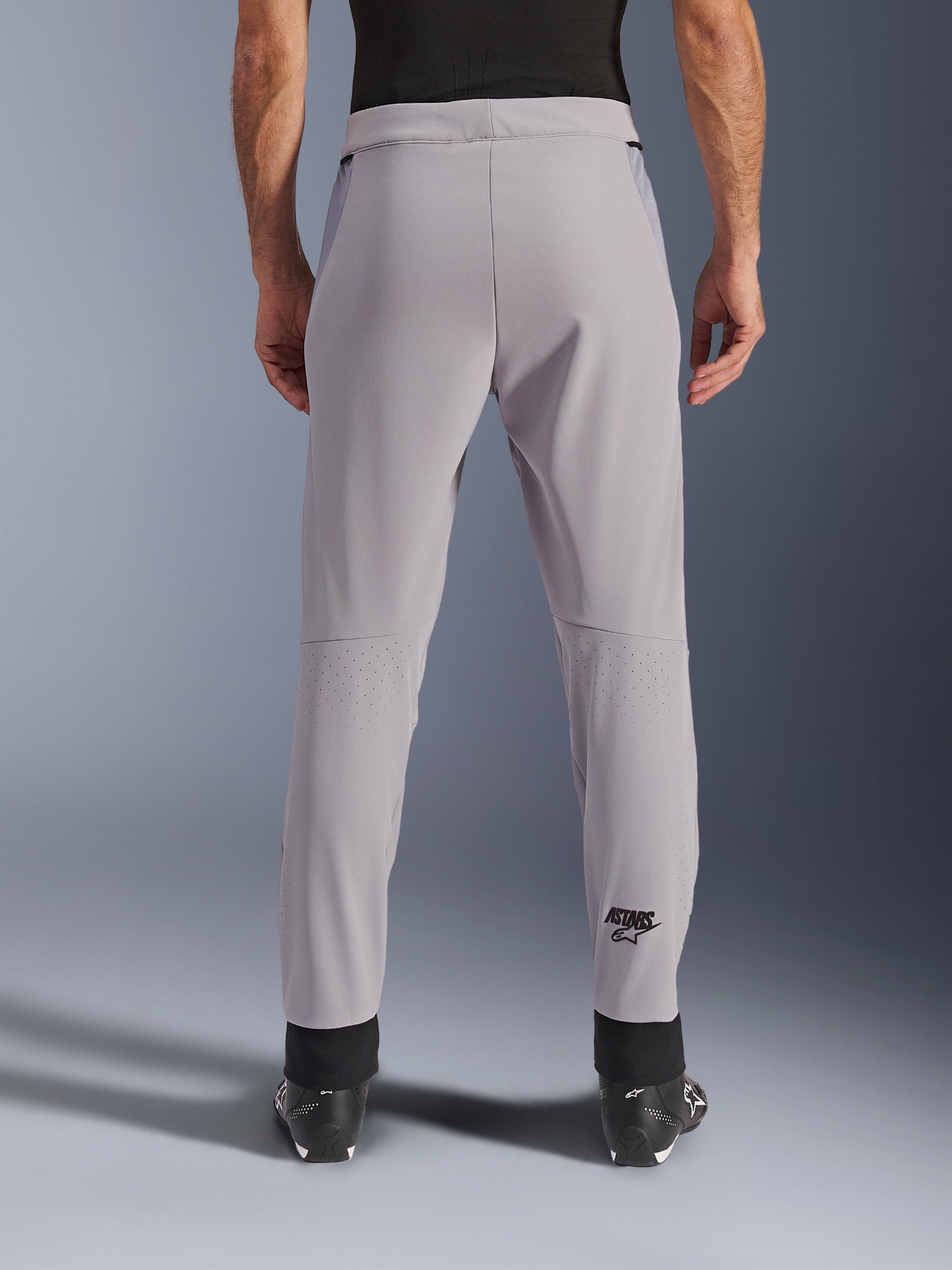Alpinestars Aeroshell Airflow Pants, motorcykelbyxor, mellangrå, baksida som visar laserperforerade zoner på vaderna och svart Astars-logotyp, textil softshell-konstruktion med svarta ankelmuddar och meshpaneler vid höfterna.