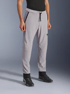 Alpinestars Aeroshell Airflow Pants, Mid Gray, lätta motorcykelbyxor med laserperforerade ventilationszoner på lår och smalben, elastiskt midjeband med dragsko och smal sportig passform, visas på en modell som bär svarta körskor.