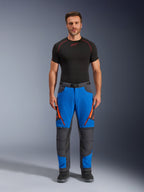 Alpinestars Maxdura Dual Pants, äventyrsmotorcykelbyxor, kungsblå och mörkgrå, orange dragkedjedetaljer, bärs med ett svart Alpinestars underställ och svarta stövlar, med förstärkta knäpaneler och en teknisk offroad-design