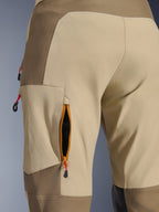 Alpinestars Maxdura Dual-byxor i Walnut Aluminum, närbild på ventilationsöppning med dragkedja på låret med orange kant och svart mesh, sandfärgat och brunt kraftigt stretch-polyamidtyg med röda dragflikar