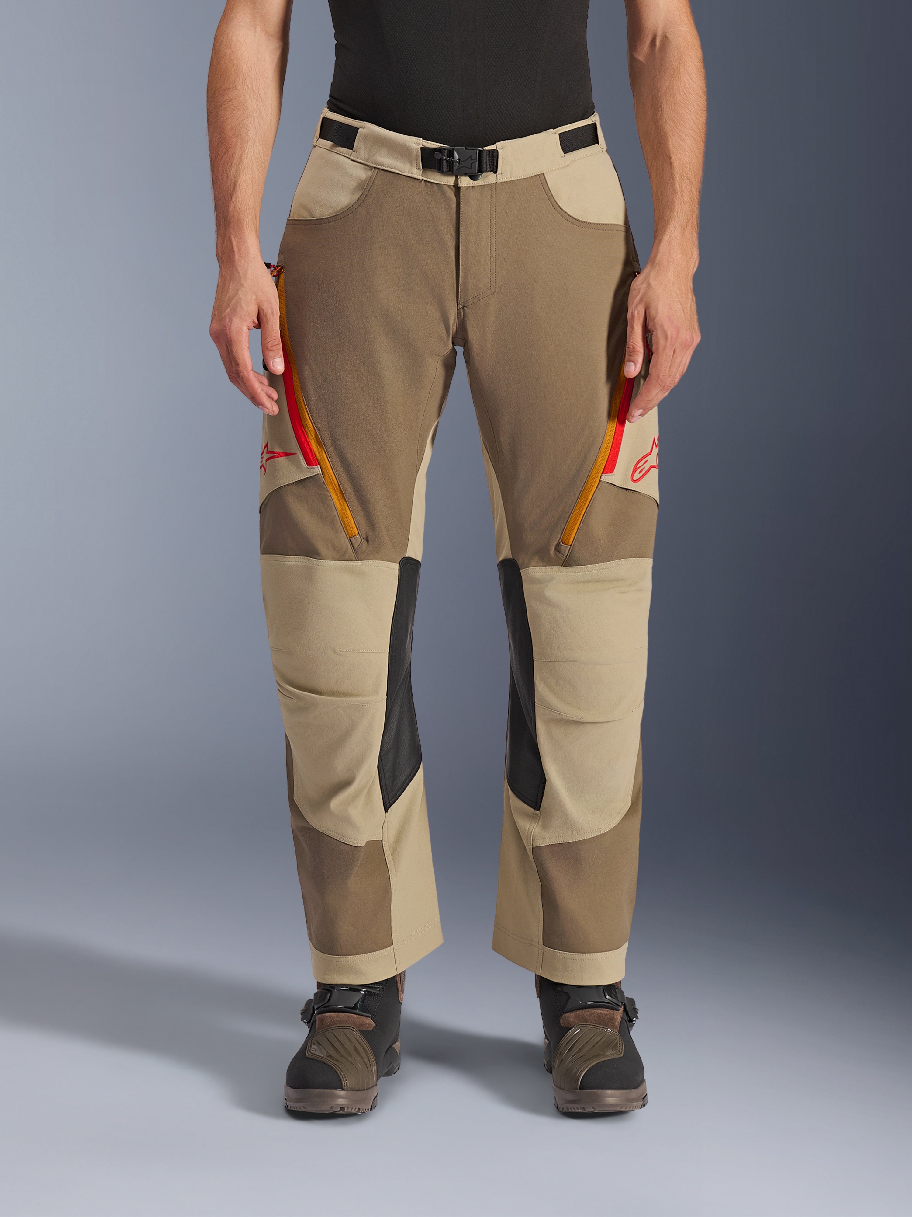 Alpinestars Maxdura Dual byxor, Walnut Aluminum, äventyrsmotorcykelbyxor med röda och orangea ventilationsöppningar med dragkedja på låren, svarta läderpaneler på knänas insida, bärs med ett svart underställ och robusta stövlar, hållbar design i flera färgtoner för dual-sport-körning