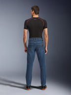 Alpinestars Flex-AST 5 Denim-byxor, Indigo Washed-blå, vy bakifrån som visar avsmalnande urban passform, bärs av modell med svart funktionströja och sneakers, skyddande MC-kläder i vardaglig stil