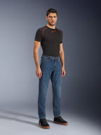 Alpinestars Flex-AST 5 Denim Pants - Short, Indigo Washed, urbana motorcykeljeans med avsmalnande passform, bärs av en manlig modell med en svart åtsittande tröja och svarta sneakers, klassisk denimstil för övergångar från väg till gata