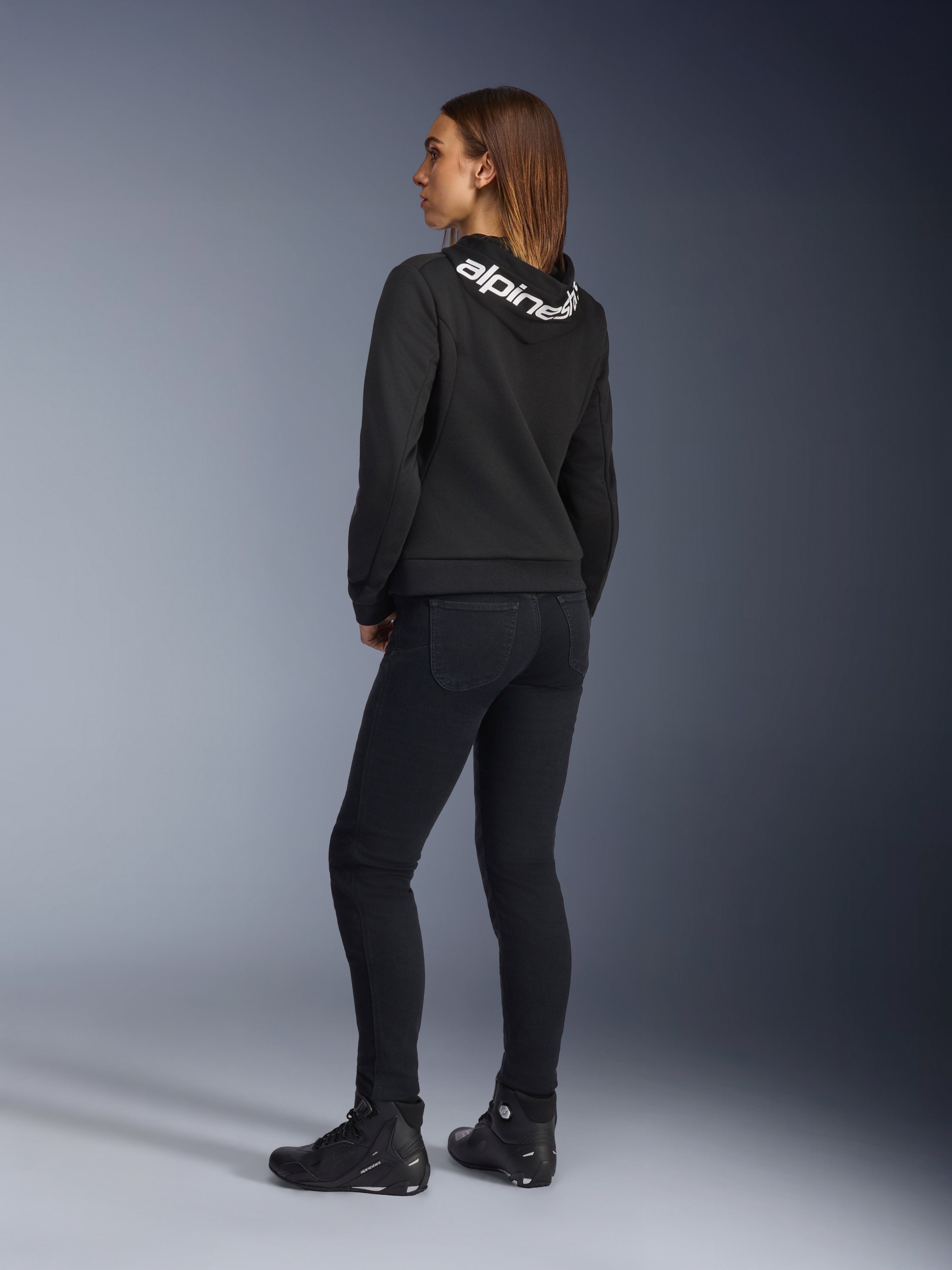 Alpinestars Daisy V3 Women's Riding Denim, Women's Motorcycle Pants, Rinse Black, rear view showing slim fit and high back waist, paired with a black Alpinestars hoodie and riding boots for an urban motorcycle look