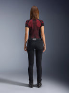Alpinestars Daisy V3 Women's Riding Denim, Rinse Black, slim fit motorcycle pants shown from behind, featuring a high-waist design and back pockets, paired with a red and black patterned technical shirt and black boots, urban motorcycle gear for women